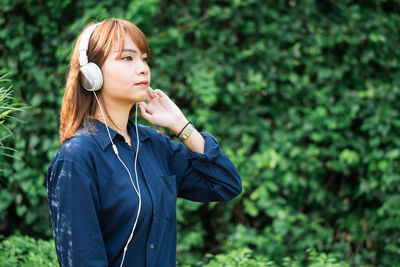 Young woman listening music while looking away in park