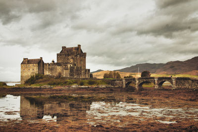 Arch bridge over river against cloudy sky