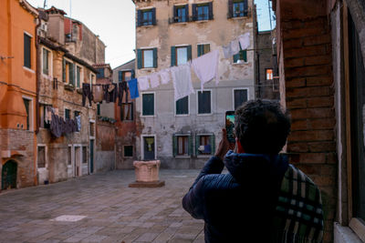 Rear view of man photographing buildings