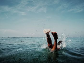 Person jumping in sea against blue sky