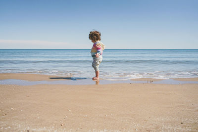 Full length of woman standing at beach against clear sky