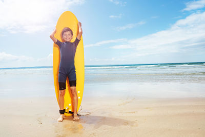 Rear view of woman standing at beach against sky