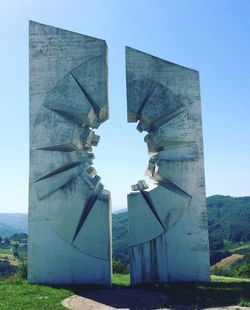 Low angle view of sculpture on field against clear blue sky