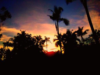 Silhouette palm trees against romantic sky at sunset