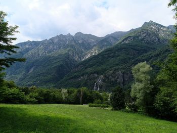 Scenic view of green landscape and mountains against sky