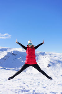 Full length of woman jumping on snow covered landscape