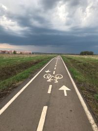 High angle view of bicycle lane sign on road against cloudy sky