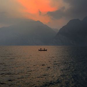 Silhouette boat in sea against sky during sunset