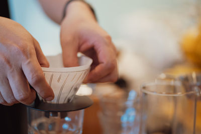 Close-up of hand holding drink on table