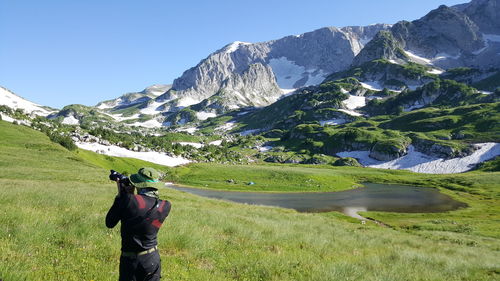 Rear view of man standing on mountain against sky