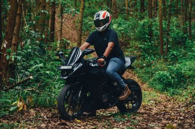 Full length of man riding motorcycle in forest