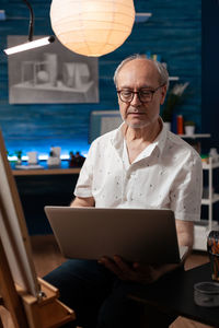 Portrait of young man using laptop at office