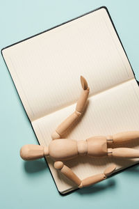 High angle view of wooden doll on book