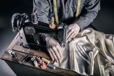 Midsection of man using sewing machine