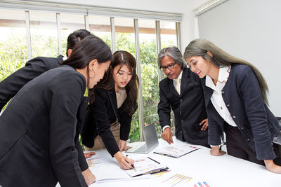 Business people analyzing charts at desk in board room 