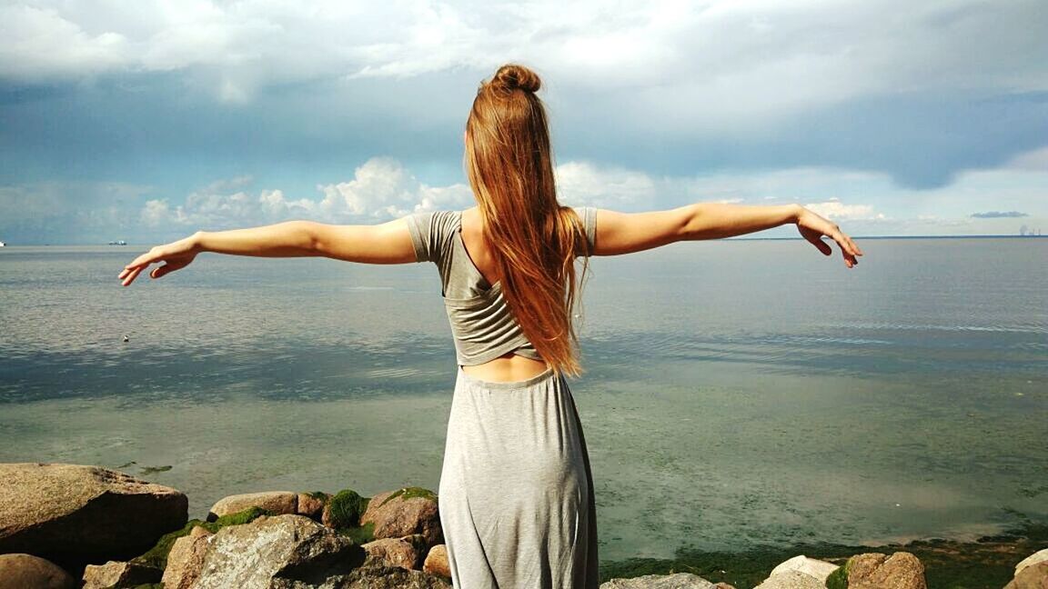 sea, rear view, water, long hair, one person, horizon over water, standing, day, arms outstretched, tranquility, nature, outdoors, cloud - sky, leisure activity, young adult, real people, sky, scenics, one young woman only, one woman only, young women, beauty in nature, adult, only women, people, adults only