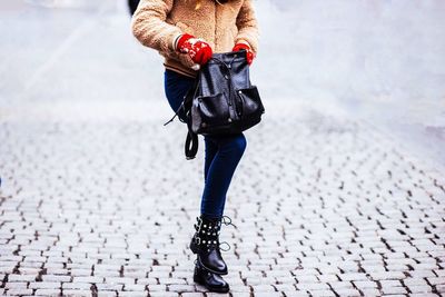 Low section of woman standing on street in winter