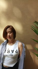 Young woman standing against wall outdoors