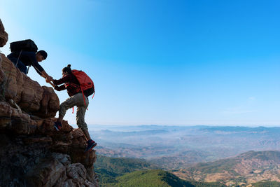 People working on mountain against blue sky