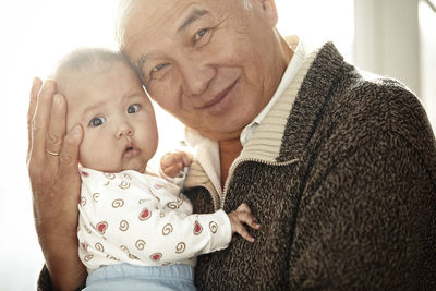 Portrait of happy grandfather head to head with his granddaughter