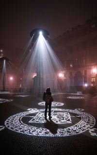 Woman standing on illuminated street at night