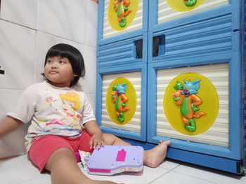 Full length of cute girl holding toy while sitting on floor