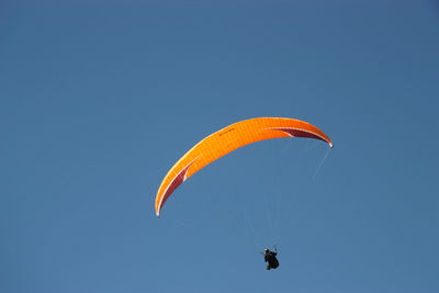 Low angle view of person paragliding against clear blue sky