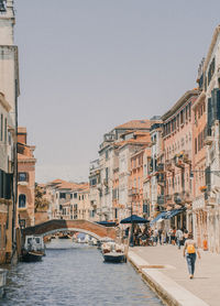 Canal amidst buildings in city against clear sky
