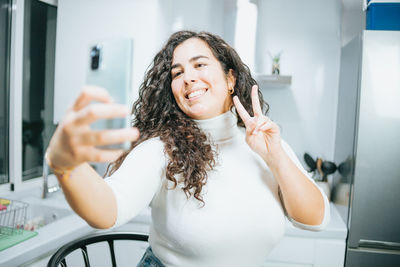 Portrait of young woman using mobile phone while sitting at home