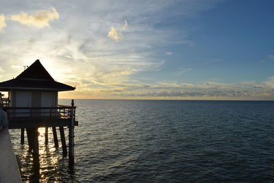 House by sea against sky during sunset