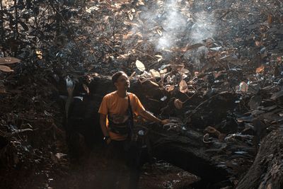 High angle view of man standing in forest by smoke
