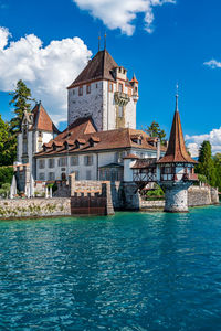 Buildings by river against sky