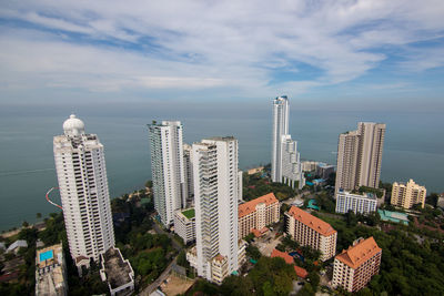 Aerial view of buildings in city against cloudy sky