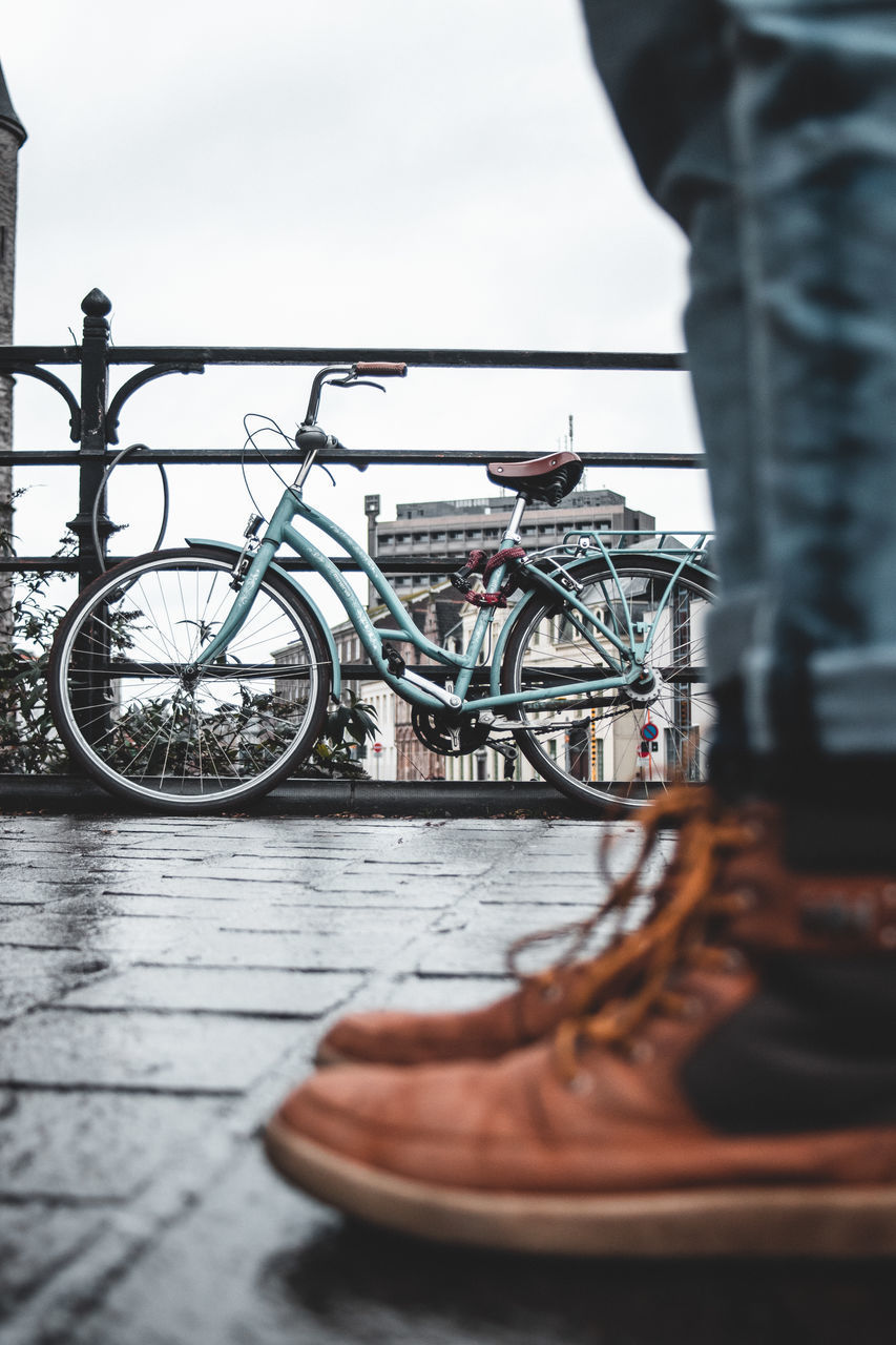 CLOSE-UP OF BICYCLE PARKED BY RAILING AGAINST RIVER