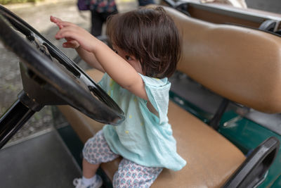 High angle view of cute girl sitting on golf cart