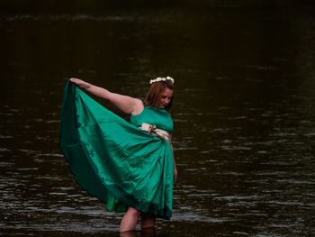 Young woman holding dress while standing in river