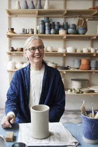 Smiling mature woman looking away while sitting at table in art class