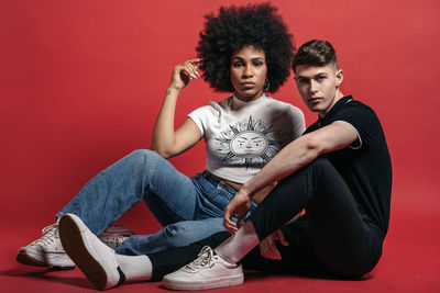 Stylish diverse girlfriend and boyfriend posing in a studio shooting with red background