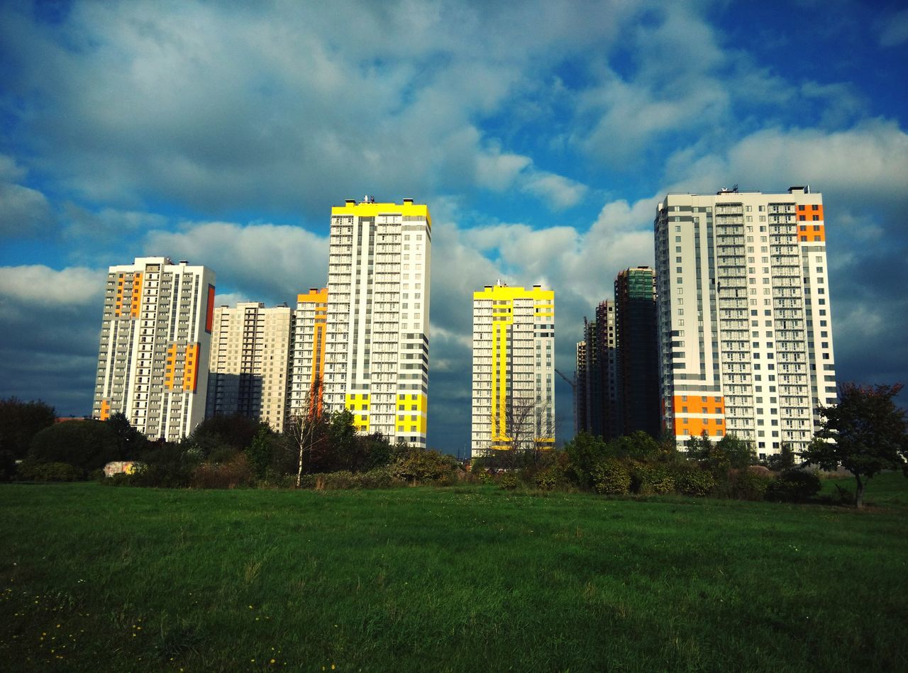 grass, building exterior, sky, architecture, built structure, cloud - sky, city, green color, modern, cloudy, skyscraper, cloud, field, tree, lawn, growth, grassy, tower, office building, tall - high