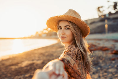Portrait of young woman wearing hat standing at beach