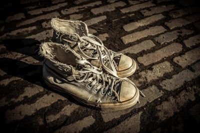 High angle view of weathered canvas shoes on footpath