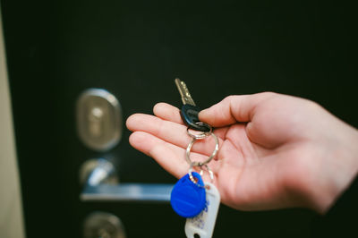Cropped hand of woman holding key against door