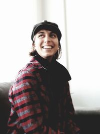 Portrait of smiling young woman standing against wall