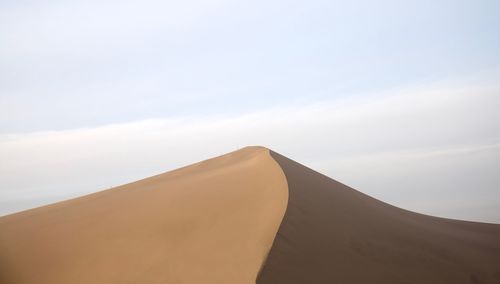 Sand dunes in desert against sky