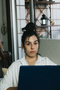 Portrait of young woman using laptop at home