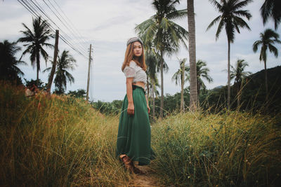 Woman standing by palm tree on field