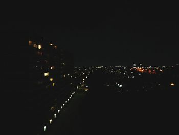 Illuminated buildings against clear sky at night