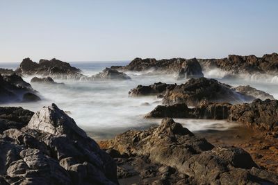 Scenic view of rocky beach against clear sky