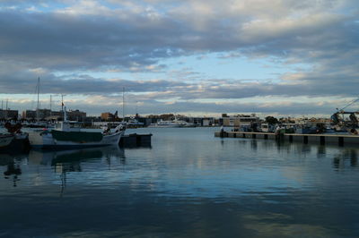 Boats moored at harbor against sky