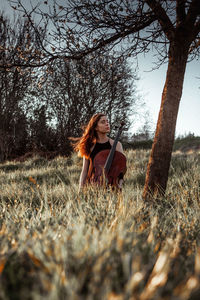 Woman sitting on field by tree